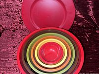 Top-down view of all six nesting mixing bowls in various colors inside largest red bowl
