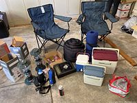 Full view of camping equipment including chairs, lanterns, stove, coolers, sleeping bag, and accessories.