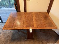 Front view of table fully open with both drop leaves extended over central gateleg support.