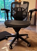 Front view of black ergonomic desk chair showing mesh back and padded armrests.