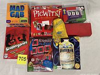 Overview photo showing the front of the boxed games including Mad Gab, PicWits!, SET, Scattergories, Scrabble Flash, and Snake Oil along with a yellow Brick by Brick bag and red Scrabble Slam! box.