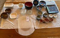 Overview photo of assorted Japanese-themed dinnerware laid on cloth including large glass platter, small bowls, plates, and chopsticks.