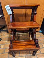 Front view of the mahogany library step stool showing two wide steps, spindle turned legs and curved side supports.