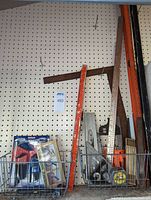 Overview of metal and wooden yard sticks, carpenter's squares, level, and tape measure in baskets