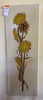 Full view of vertical rectangular crewel sunflower panel showing five sunflowers with stems and leaves on beige linen fabric.