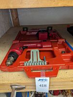 Milwaukee 3/8 inch cordless drill in red plastic carrying case with drill bits inserted in a holder, spare battery slot empty.