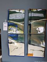 Four ceramic plaques mounted on a wall showing full polyptych layout with abstract art in green, blue, white, and brown hues with visible text handwriting on two upper panels.