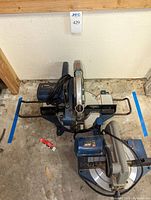 Two Ryobi miter saws placed side by side on the floor, showing overall layout and condition.