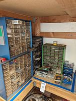 Overall view of blue and green plastic sorting drawers containing assorted screws, bolts, washers, and nuts organized for hardware storage.
