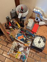Wide view showing assorted hand tools, flashlight, hardware items, and containers packed in cardboard box.