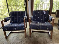 Front view of two wood frame chairs together, showing duck-themed blue padded seats and back cushions with wooden arms and legs
