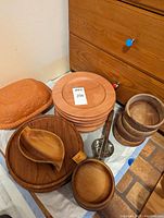 Photo of the wooden plates stacked, wooden bowls stacked, wooden ladle, metal ladle, small nut dish, with Master Clay Roaster lid.