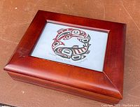 Closed wooden box with glass inset showing signed and numbered Indigenous West Coast salmon artwork "Salmon Circle" by George Littlechild.