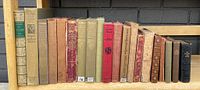 Wide view of all antique hardcover books on shelf, showing variety of colors and sizes