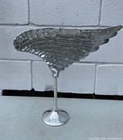 Front left angle view of the solid cast aluminum left wing sculpture showing feather details and polished pedestal base.