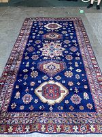 Full view of a blue geometric medallion area rug laid flat on concrete