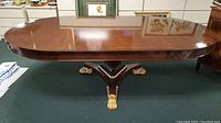 Front view of extended table showing mahogany top and central pedestal with gilt claw feet