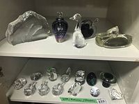 Two-tier shelf showing five larger items on top and eleven small figurines and paperweights on bottom