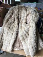 Full view of the fur cape and jacket showing the fur texture and lining, with fur appearing soft and cream-colored with slight brown tones.