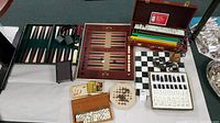 Two wood backgammon boards side by side with checkers, dice, leather strap, cards and hexagonal solitaire board