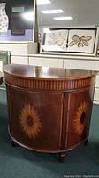 Front view of demilune cabinet showing curved front with sunburst inlay motifs