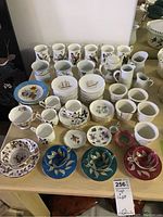 Front view of assorted mugs, cups, saucers and plates on wooden table