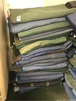 Full stack of folded moving blankets in assorted colors.