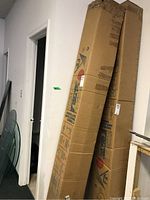 Two long cardboard boxes labeled FIM leaning against a wall