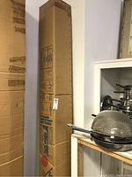 Full view of boxed umbrella leaning against wall and shelving