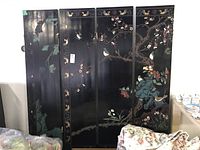 Full view of the four-panel Asian themed folding room screen with artwork showing birds, tree branches, and flowers on a black lacquered background.