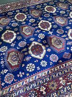 Full view of rug laid flat showing blue field and geometric medallions