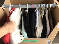 Box of hanging garments showing nine items including blazers, sweaters and blouses