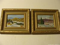 Two small framed Canadian landscape paintings next to each other on a wall, showing winter scenes with cabins and trees.