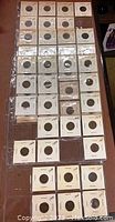 Photo of Canadian pennies in individual white cardboard holders placed in plastic sleeves in a folder, showing about 30 coins with visible dates stamped on holders and coins.