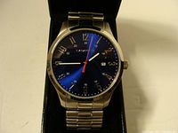 Front view of Caravelle by Bulova men's wristwatch showing blue dial and stainless steel flex band inside a black presentation case.