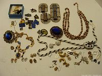 Full view of multiple jewelry items spread out, including necklaces, earrings, and pins.
