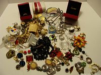 Photo showing an overview of assorted jewelry including a Cartier ring, various clip earrings, beads, and decorative pins.