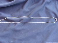 Full view of the entire 18 inch box chain necklace laid on blue fabric background.