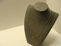 Sterling silver box chain necklace displayed on a grey necklace bust.