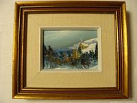 Full view of framed oil painting showing winter landscape with house and trees, gold frame with beige mat