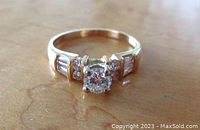 Frontal view of ring on wooden surface showing central and shoulder diamonds