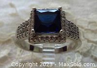 Front view of vintage silver-tone ring showing square blue stone and diamond halo.