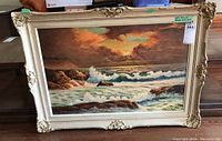Full view of the framed oil painting with seascape scene, signed by artist, showing some wear and damage on the ornate cream-colored wood frame.