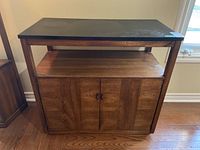 Front view of the wood laminate cabinet with closed cupboard doors and open middle shelf, showing laminate top surface and wood grain finish.