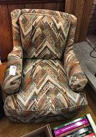 Armchair showing front and side angle with geometric patterned fabric upholstery in earth tones.