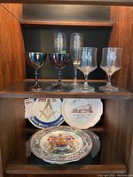 Entire lot displayed together showing glassware on top shelf and decorative plates on bottom shelf
