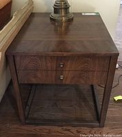 Front view of Kaufman Furniture end table with a lamp on top, showing solid wood construction and drawer front.