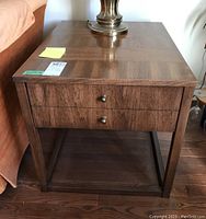 Front view of the brown wooden Kaufman Furniture end table showing the tabletop finish, two round metal knobs on the drawer, and the overall structure.