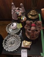 Full lot displayed on table including glass ashtrays, ceramic bird figures on wood stumps, circular figure candle holders, Noma light timer and golden boat-shaped decorative item.