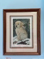 Full view of framed print showing puppy sitting in snow beneath pine branches, triple matted with beige and brown mats in wood frame.